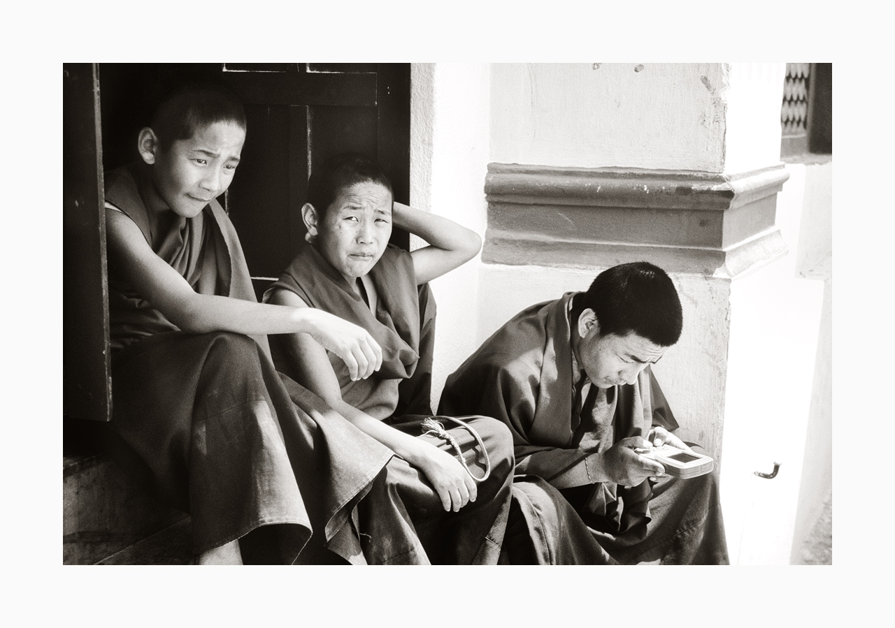 Fine art black and white image of monks playing with a Gameboy in the '90s, Nepal.
