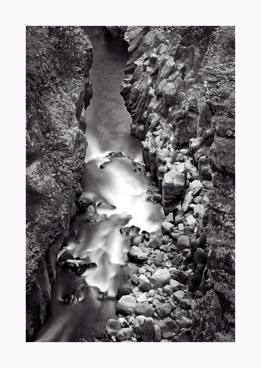 Fine art black and white image of basalt column walls and water flow of Takachiho Gorge, Japan.